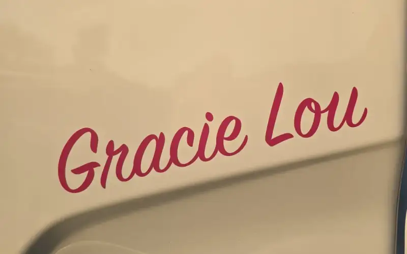 The name Gracie Lou painted in pink script on the cab of an NCG Movers truck