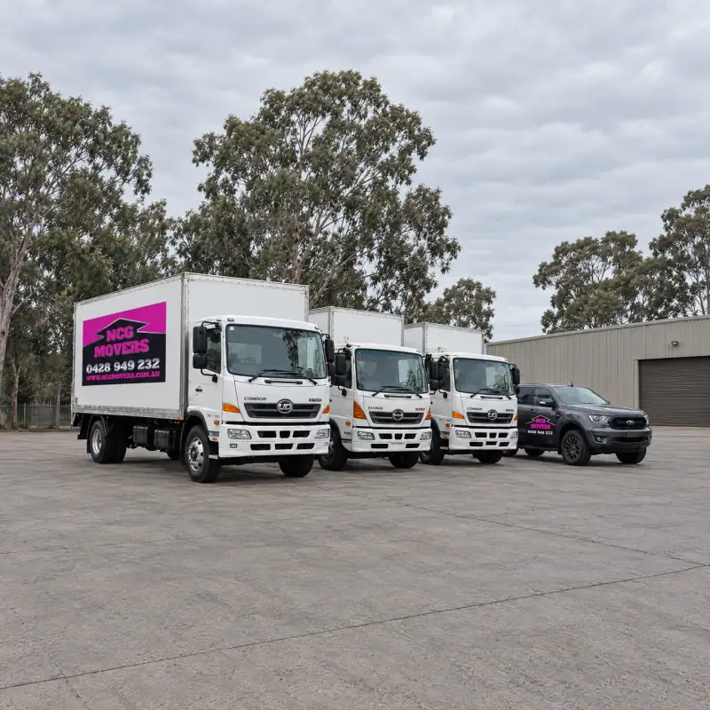 Three NCG Movers trucks and the NCG Movers ute parked side by side on a depot yard